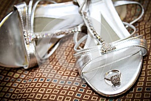 Bride`s Engagement Ring Resting on her Wedding Shoes