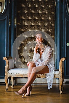 Young beautiful bride in white negligee preparing to wedding ceremony