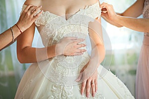 Bride`s girlfriend helps bride dress up her wedding dress