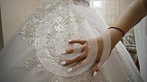 Bride`s hand caressing a wedding dress. Closeup