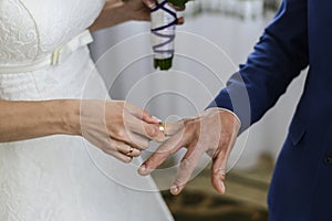 Bride's hand putting a wedding ring