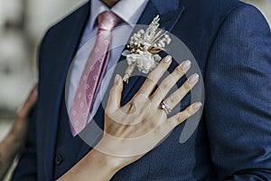 Bride`s hand and rings on groom`s blue outfit