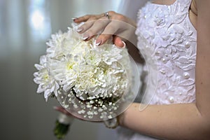 Bride's hand touching her delicate wedding bouquet