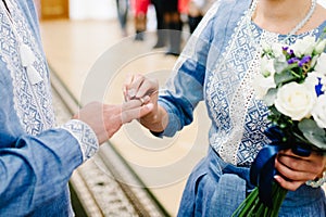 The bride`s hand wears an engagement gold ring on the groom`s finger. Wedding day. Hands with wedding rings. Close up. Bride and