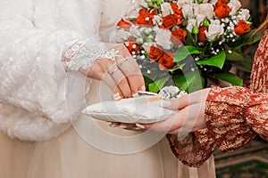 The bride`s hand in the wedding glove takes the marriage ring. Close-up of wedding rings