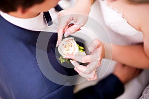 The bride s hands gently touch the buttonhole in the groom s pocket. Top view