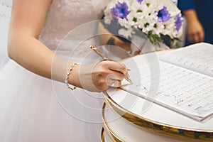 Bride`s hands put signature on consent to marriage in registry office