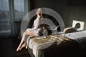 Bride`s morning. Fine art wedding. Portrait of a young bride in white lace boudoir with wavy blonde hair and a bouquet