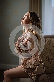 Bride`s morning. Fine art wedding. Portrait of a young bride in white lace boudoir with wavy blonde hair and a bouquet