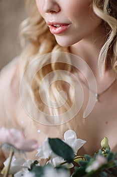 Bride`s morning. Fine art wedding. Portrait of a young bride in white lace boudoir with wavy blonde hair and a bouquet