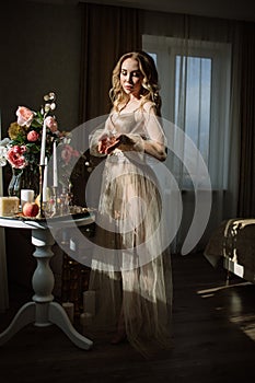 Bride`s morning. Fine art wedding. Portrait of a young bride in white lace boudoir with wavy blonde hair and a bouquet