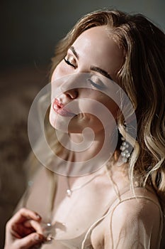 Bride`s morning. Fine art wedding. Portrait of a young bride in white lace boudoir with wavy blonde hair and a bouquet