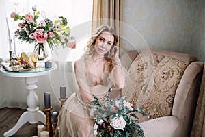 Bride`s morning. Fine art wedding. Portrait of a young bride in white lace boudoir with wavy blonde hair and a bouquet