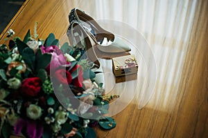 Bride`s shoes, wedding bouquet, two gold rings. Wedding accessories for the newlyweds, top view