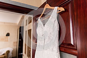 Bride`s wedding dress hanging on the door in the room