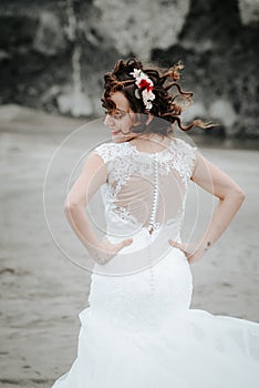 Bride on the seacoast. Fluttering hair and flowers in her hair looking away