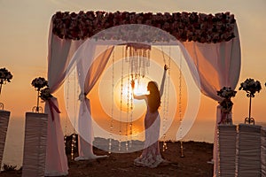 Bride silhouette. Wedding ceremony arch with flower arrangement