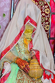 Bride sits on chair and  hidden har face with a golden clutch