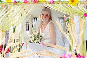 Bride Sitting Under Decorated Canopy At Wedding