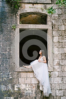 he bride is sitting on the window of the ancient abandoned Arza fortress on the Mamula island