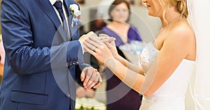 Bride slipping ring on finger of groom at wedding