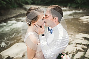 Bride smiles with closed eyes while groom touches her face delicately