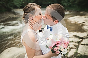 Bride smiles with closed eyes while groom touches her face delicately