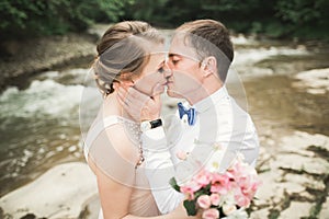 Bride smiles with closed eyes while groom touches her face delicately