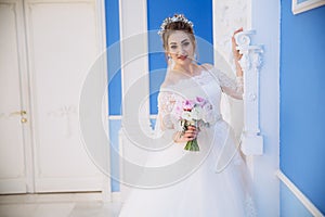 The bride smiles and walks through the great hall with the columns, examines and touches them. In the bride`s hand is a