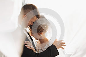 Wedding portrait. The groom in a black suit and the blonde bride are hugging