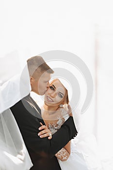 Wedding portrait. The groom in a black suit and the blonde bride are hugging