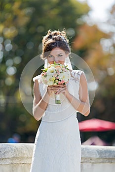 Bride sniffs bridal nosegay on open air