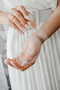 The bride splashes perfume on her wrist