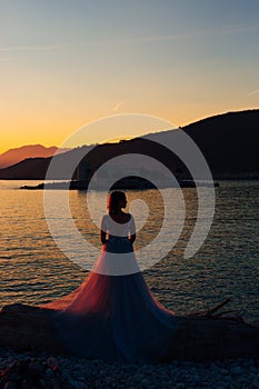 the bride standing on the on the beach of the Mamula island against the background of the Arza fortress at sunset
