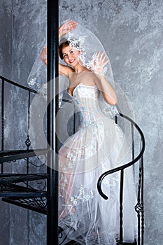 Bride standing on spiral staircase in loft apartment. Woman dressed in wedding dress with lace, copy space for text