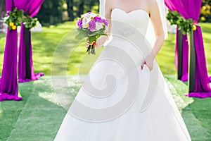 Bride standing in wedding archway with chairs on on each side