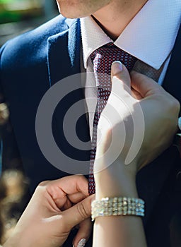 Bride straightens to groom his tie, close-up of hands