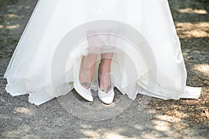 Bride in summer at a wedding raises her dress and shows her legs