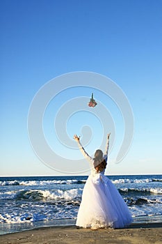 Bride throwing bouquet in sea