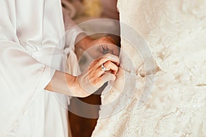 bride touch white dress by hands with ring before begining preporation to ceremony photo