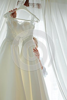 The bride is trying on a wedding dress, looking in front of her