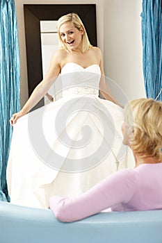 Bride trying on wedding dress with sales assistant