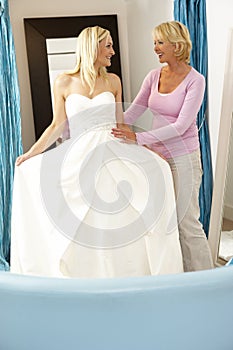 Bride trying on wedding dress with sales assistant
