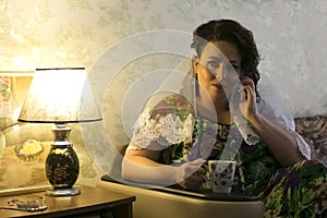 The bride is waiting for a call from the groom and drinks coffee in the morning