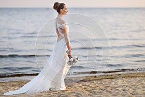 Bride walking along sea coast in wedding dress