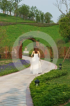 Bride walking in park with wooden gate photo