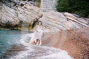 Bride walks on the beach holding the hem of the dress with her hands