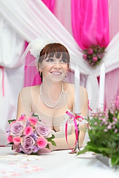 Bride wearing dress sits at table with candles