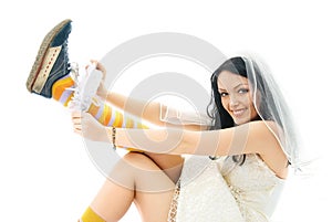 Bride wearing sporting shoes puts on a garter photo