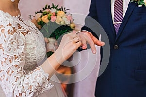 Bride wears a gold ring on groom`s finger at wedding ceremony